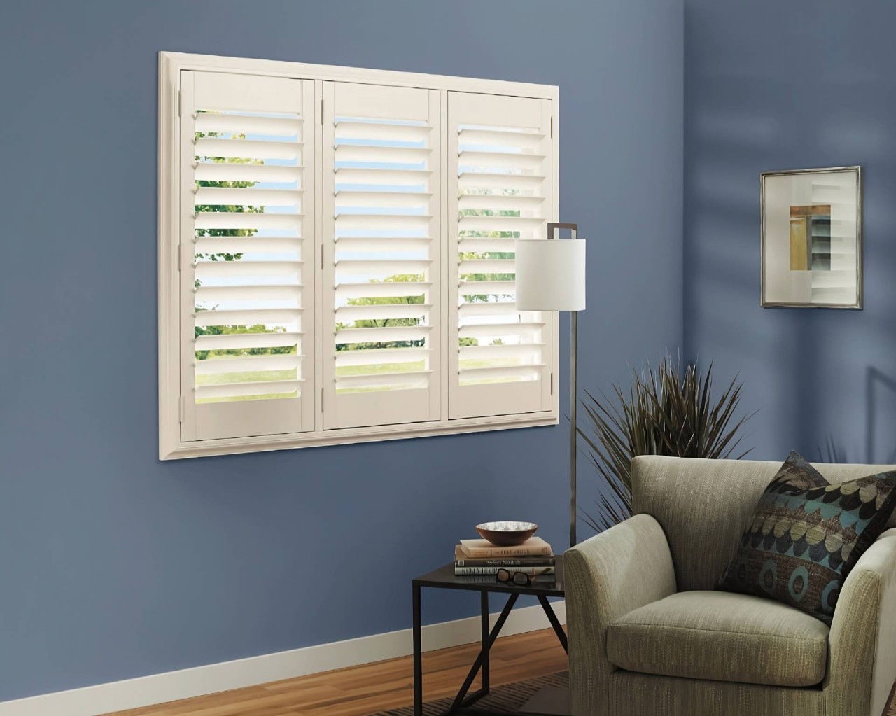 White Heritance® Wood Shutters on a small window in a blue and green-themed living room at WTI Inc. near Concord, MA